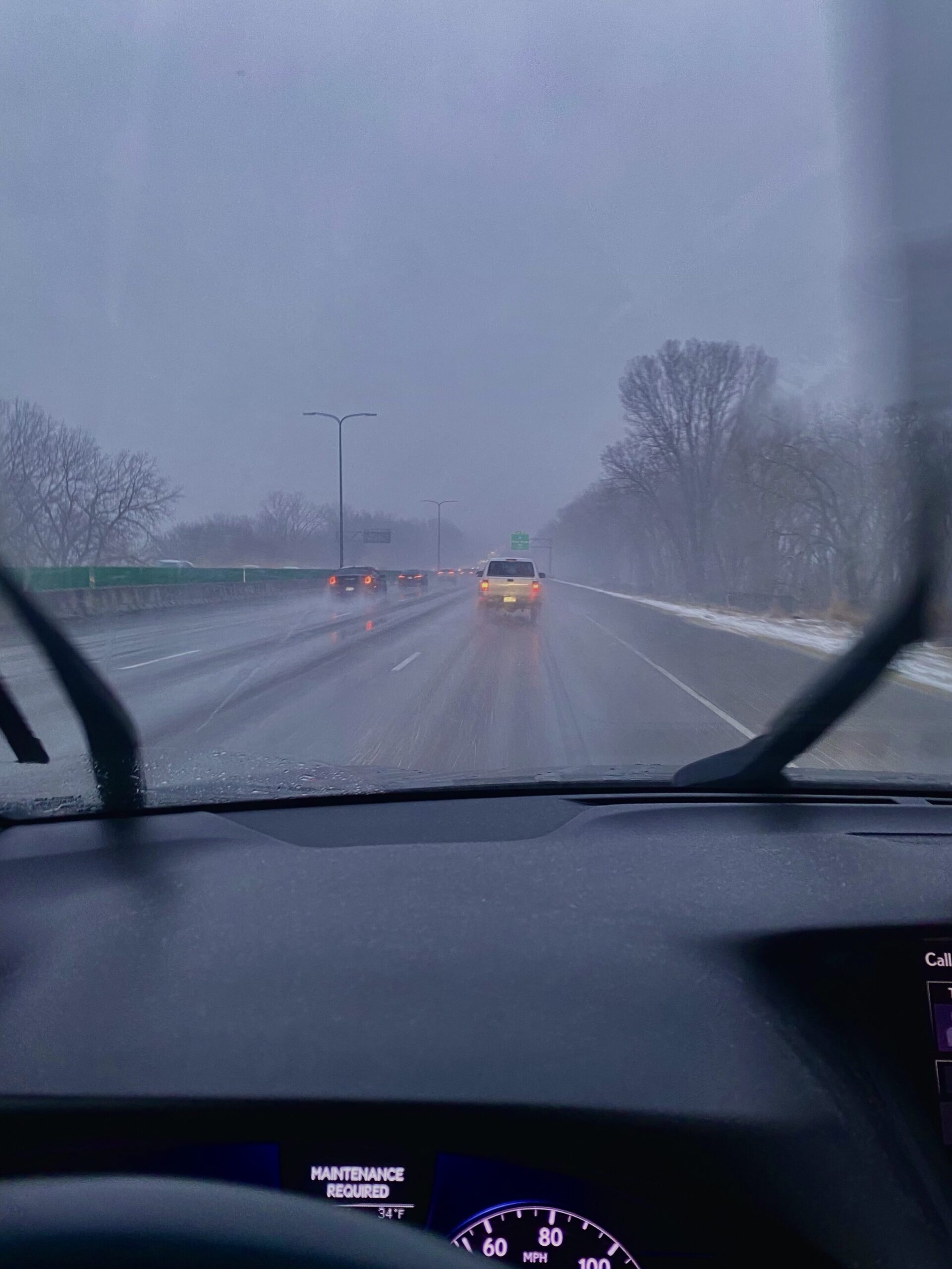 Inside of a car, driving through a snowy highway.